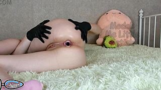 Pastorka v lateks rokavicah piša, z ritnim čepom v riti, si drgne velik klitoris