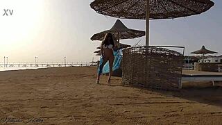 Beautiful young girl flashes big tits and ass without panties on public beach.