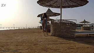 Beautiful young girl flashes big tits and ass without panties on public beach.