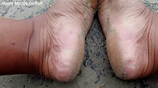 hot girl walks barefoot on beach with dirty feet soles. she shows wet foot fetish play outdoors in public