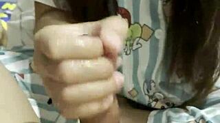 Asian girl gives her boyfriend an amazing handjob in the bedroom as a cute couple