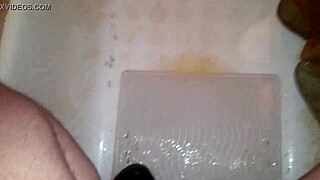 A guy jerks off while peeing and shoots his jizz everywhere.