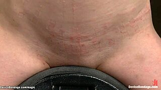 Lesbisk hängande från talja vibreras av maskin. Hennes bundna kropp skakar av intensiv njutning.